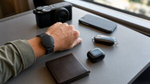 Person using a modern smartwatch while everyday gadgets rest on a desk nearby.